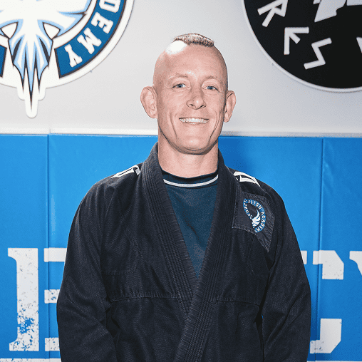 Jiu-Jitsu instructor smiling in gi at Legacy Jiu-Jitsu Academy training facility.