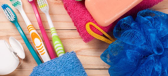 Toothbrushes, soap, and washcloths on wooden surface.