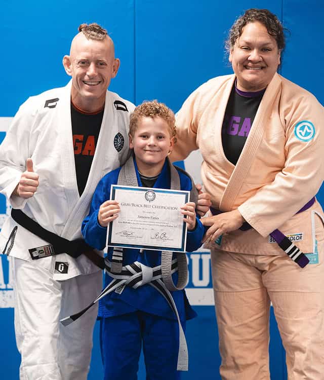 Young student receives a belt and certificate after completing martial arts training.