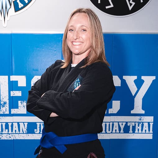 Jiu-Jitsu instructor smiling confidently in gi with blue belt at Legacy Jiu-Jitsu Academy.