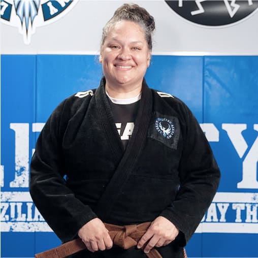 Female Jiu-Jitsu instructor smiling in gi at Legacy Academy.